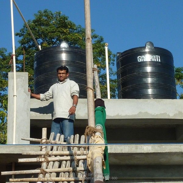 Pater Jaison vor den beiden Wassertanks Pater Jaison vor den beiden Wassertanks